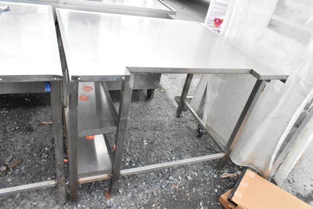 Stainless steel table with sturdy frame and lower shelf, shows light use. Visible labels and markings on legs.