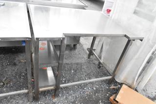 Stainless steel table with sturdy frame and lower shelf, shows light use. Visible labels and markings on legs.