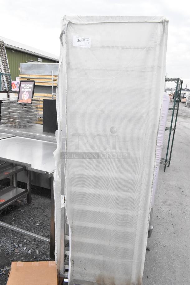 Metal commercial pan transport rack with cover on commercial casters. Appears in used condition with visible labels.