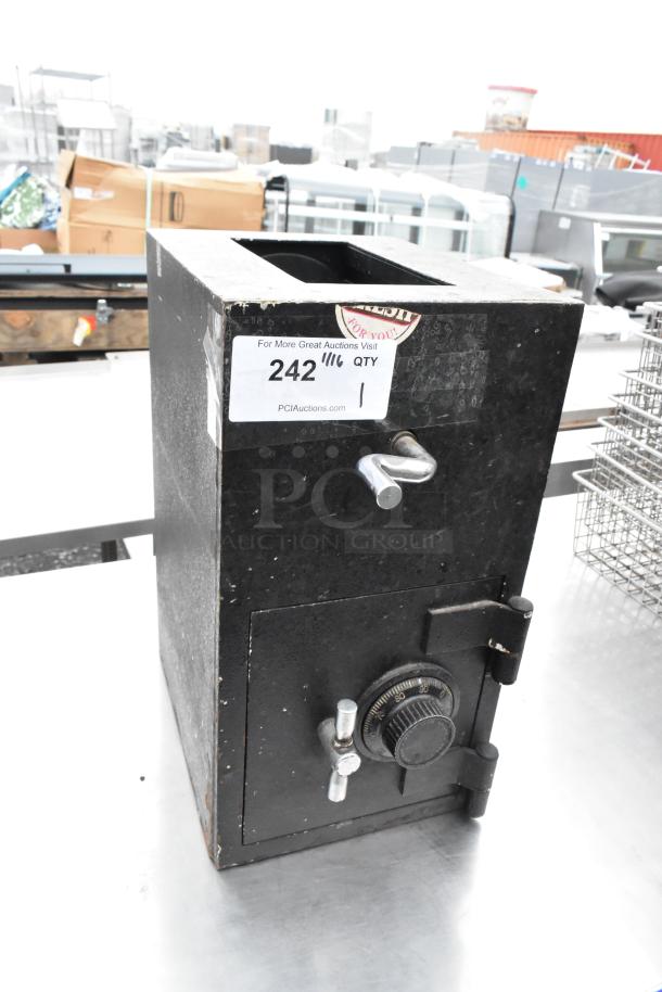 Black drop safe with manual lock, no combination included. Auction label indicates item number 242. Visible wear on surface.