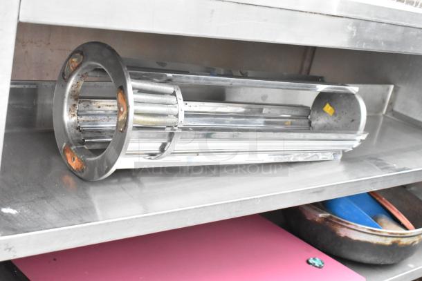 Stainless steel table with under shelves and contents, on commercial casters. Features reflective surface and visible wear.