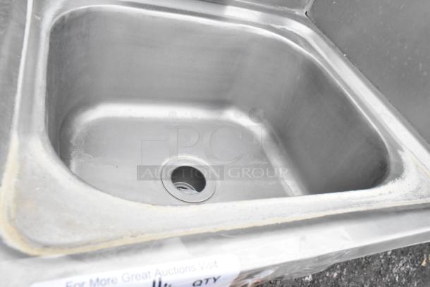 Stainless steel commercial single bay sink, includes faucet and handles, in used condition. Visible markings suggest durability.