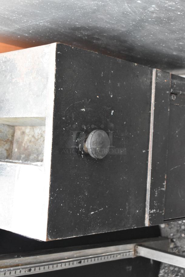 Black metal single compartment safe, no combination included. Features a dial on the front. Some visible wear.