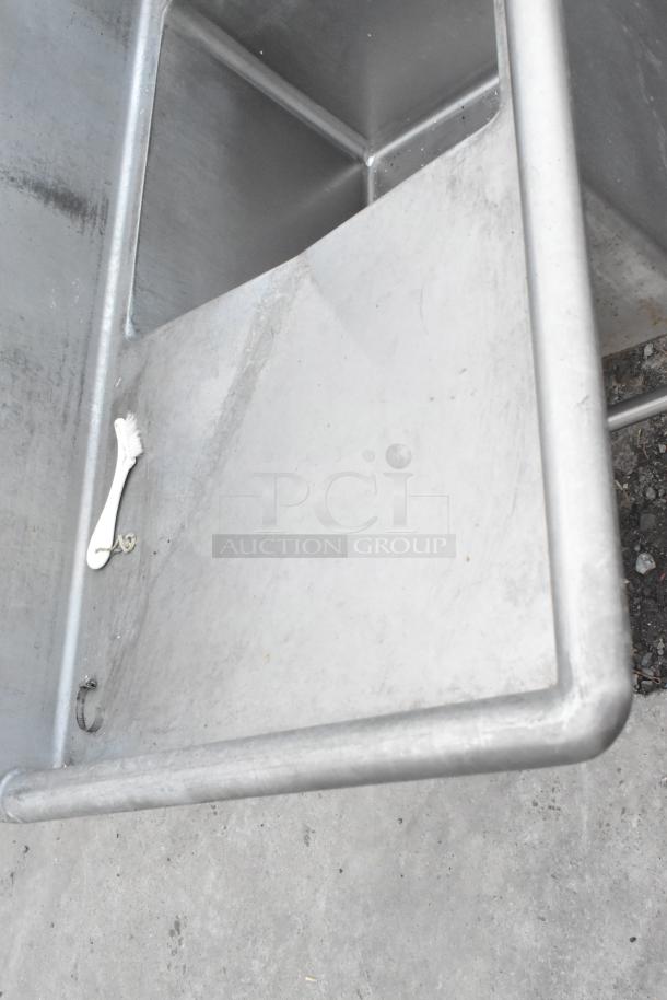 Stainless Steel 3 Bay Sink with dual drain boards, industrial-grade, showing wear, includes attached white brush.