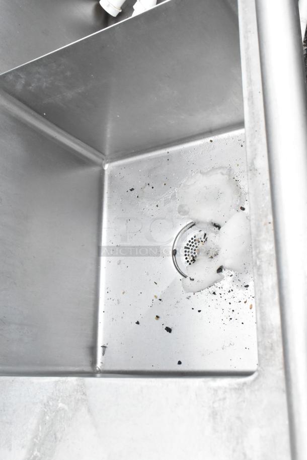 Stainless steel 3-bay sink with dual drain boards, some debris visible, sturdy construction, ideal for commercial kitchens.