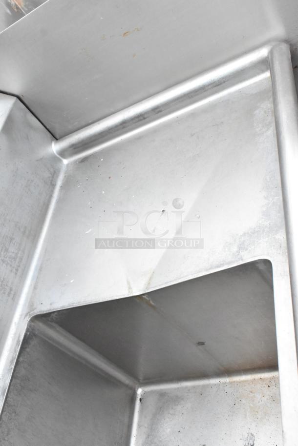 Stainless steel 3 bay sink with dual drain boards, showing light wear. Ideal for commercial use, durable and spacious.