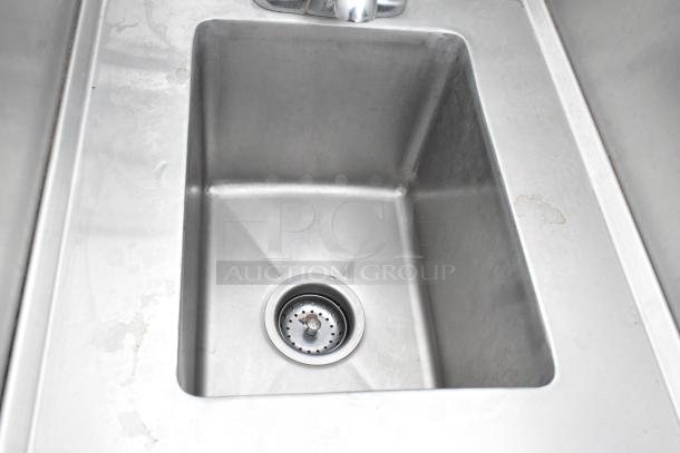 Stainless steel single bay sink with faucet, handles, splash guards; well-maintained with minor surface marks.