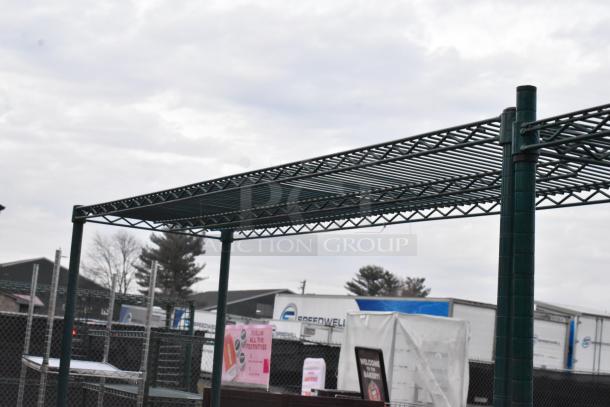 Green 4-tier wire shelving unit, outdoor setting, sturdy metal construction. Buyer must dismantle, freight charges apply.