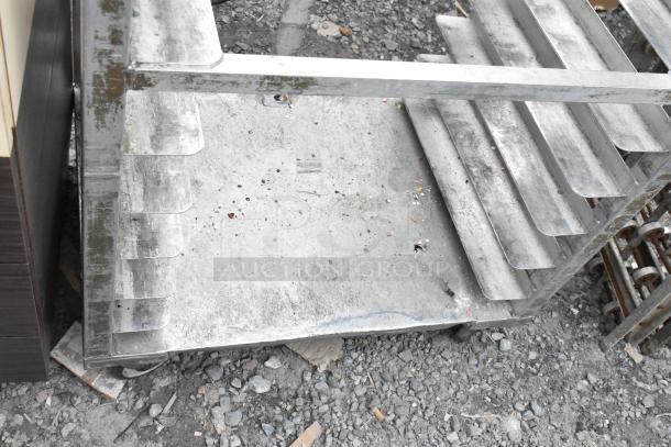 Metal commercial pan transport rack on casters, in used condition, visible wear and rust spots, suitable for industrial use.