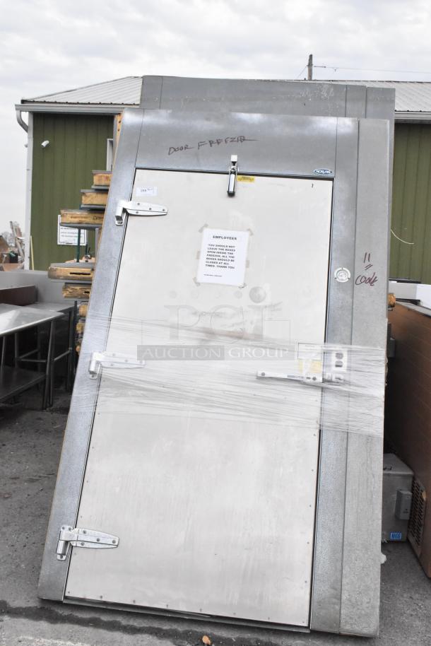 Norlake walk-in box door, labeled "Door Freezer," with hinges, latches, and caution sign visible; exterior view.
