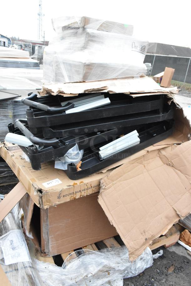 A stack of black reinforced table bar alloy parts in open, damaged packaging. Auction lot of scratch and dent items.