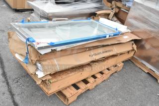 New scratch and dent sneeze guard on a pallet, wrapped and labeled "FLAT GLASS 360SNZGD12," in original packaging.