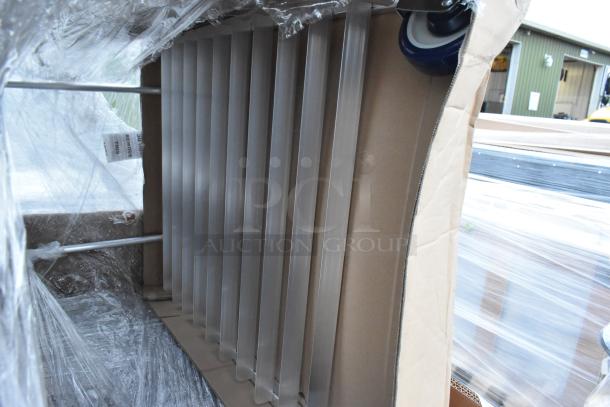 New metal pan racks wrapped in protective plastic, part of scratch and dent auction items. Includes visible wheels.