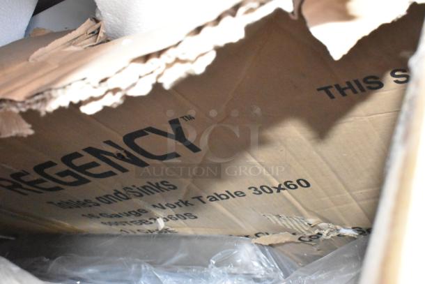 Cardboard box labeled "Regency," containing a 30x60 work table, slightly damaged packaging.