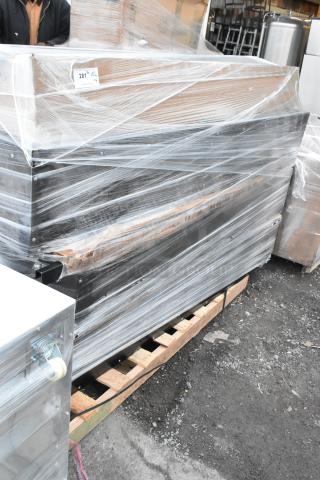 Four brand new black metal lockers wrapped in plastic, scratches and dents visible, on a wooden pallet. Label reads "281."