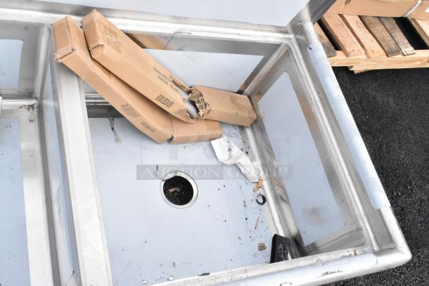 Brand new Regency 78" stainless steel commercial sink, three compartments, no drainboards, visible dents and debris.