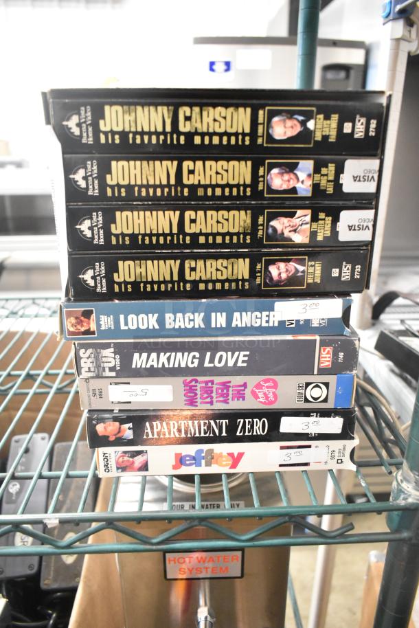 Stack of 18 VHS tapes including "Jeffrey," "Three Men and a Baby," and "Johnny Carson Collection." Tapes feature original labels and varying conditions.