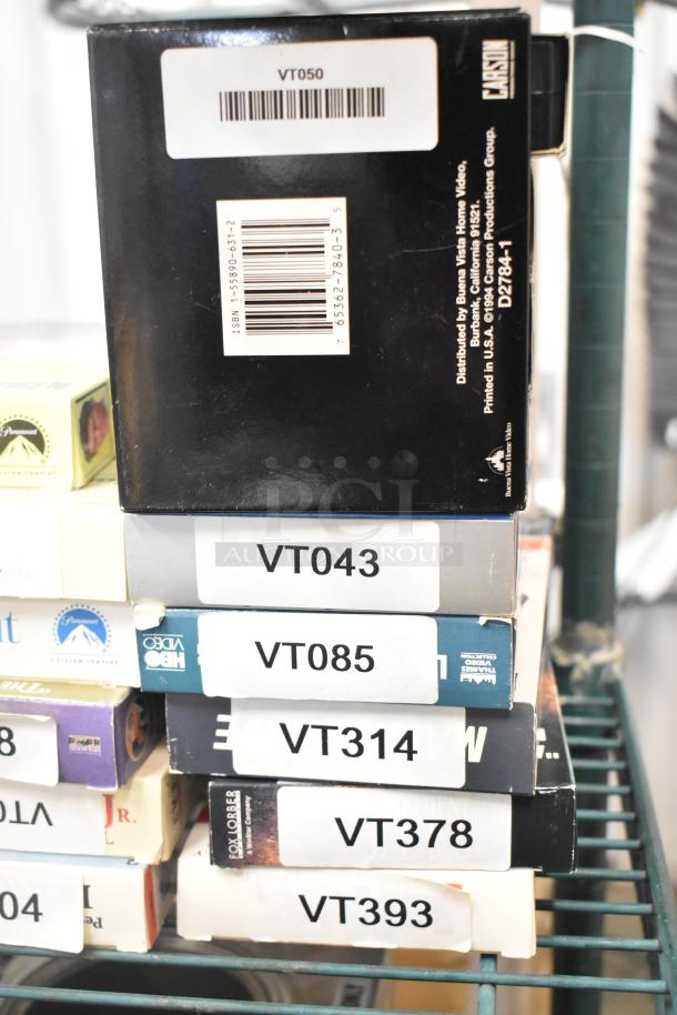 Stack of 18 VHS tapes, including titles like "Jeffrey" and "Three Men and a Baby." Labels indicate catalog numbers.