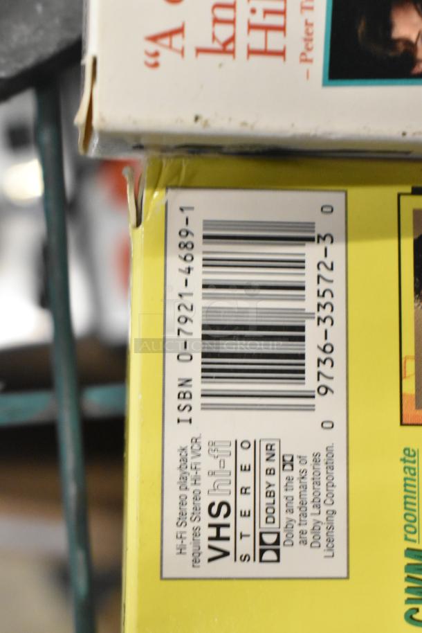 Stack of 18 VHS tapes including "Jeffrey," "Three Men and a Baby," and "Johnny Carson Collection." Visible label shows Hi-Fi Stereo playback notice with ISBN 0-7921-4689-1.