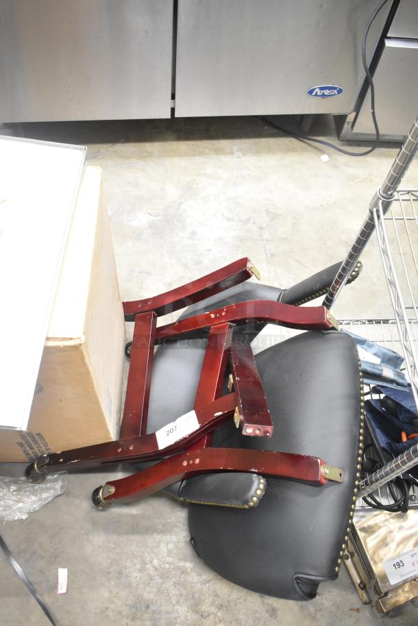 Disassembled chair pieces including dark wood legs and a black cushioned seat with stud detailing. Condition appears used. Tag visible with "207."