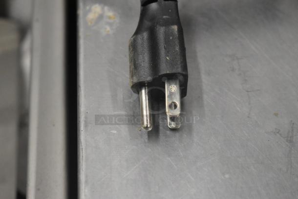 Close-up of a power plug for Globe Chefmate GC 512 meat slicer, 115 volts, 1 phase. Plug on stainless steel counter.