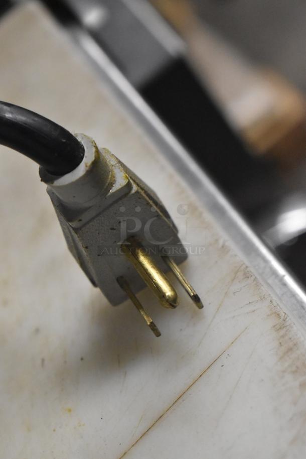 Close-up of a three-prong electrical plug for the True TSSU-72-30MB-ST-HC prep table, showing minor wear.