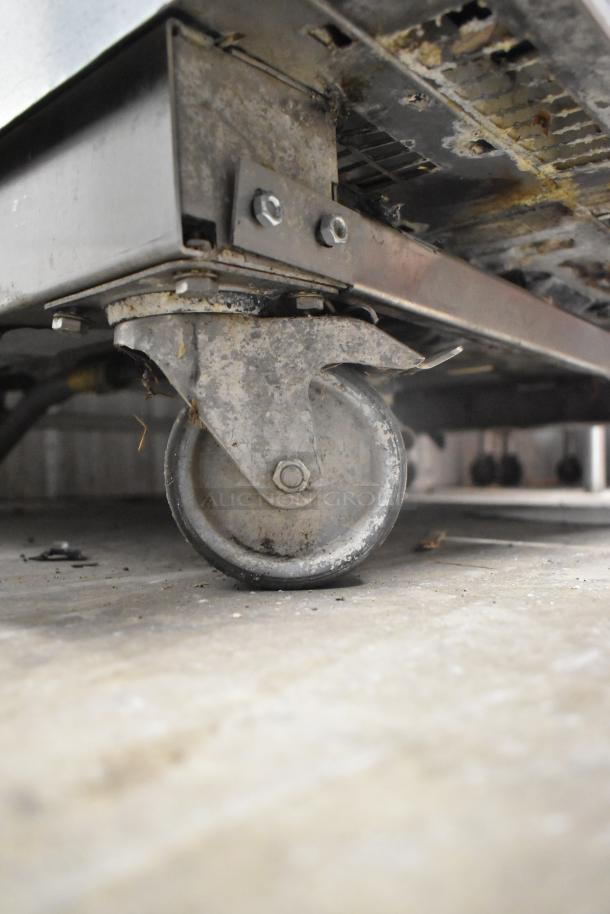 Close-up of a caster wheel on a Rational SCCWE62/SCCWE102 commercial convection oven, showing some wear and rust.