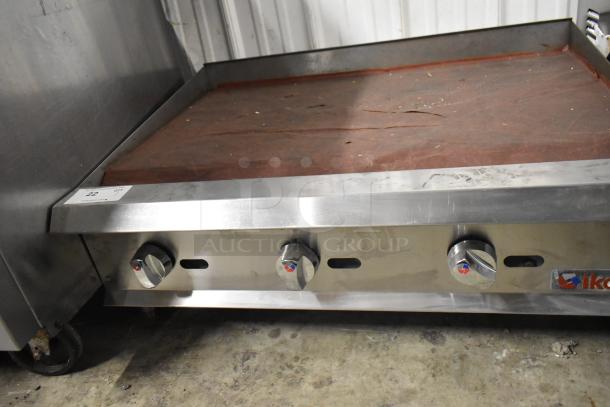 Ikon Stainless Steel Gas Flat Top Griddle, commercial countertop model. Features sturdy knobs and visible wear on cooking surface.