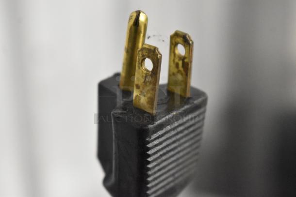Close-up of a three-prong plug from a Manitowoc commercial ice machine, showing slight wear on prongs.