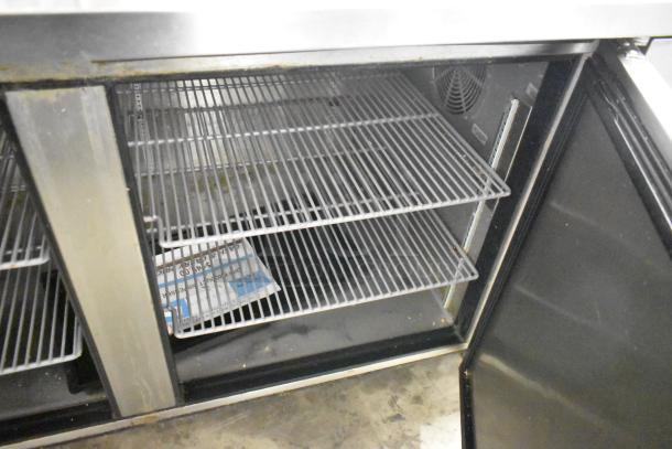 2019 True TPP-67 stainless steel commercial pizza prep table, interior view, shows shelves, on commercial casters, 115V, 1 phase.