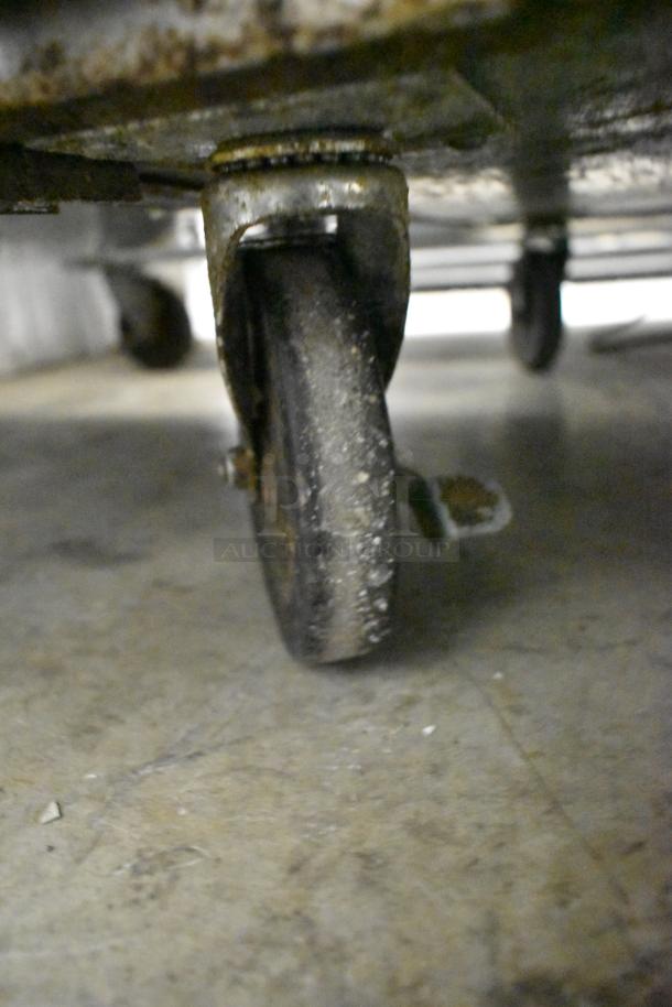 Close-up of a commercial caster on the 2019 True TPP-67 Stainless Steel Pizza Prep Table, showing wear and use.