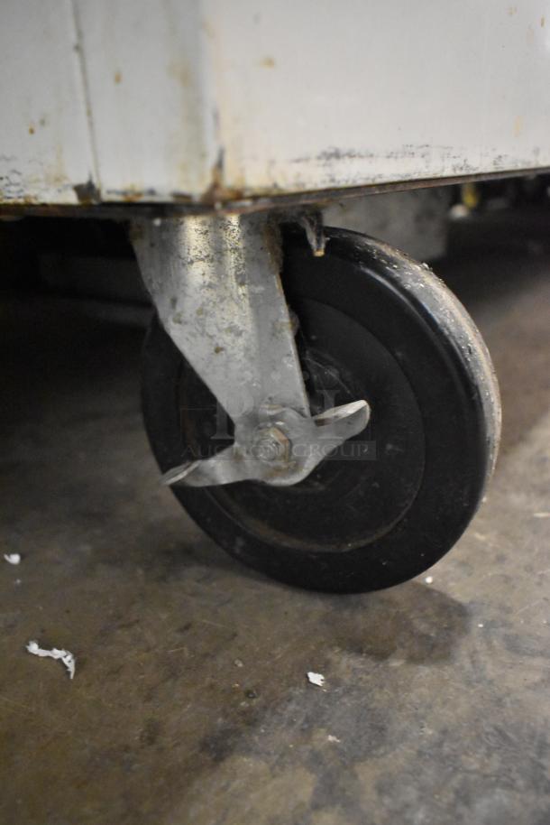 Beverage Air SMF49 commercial milk cooler on caster, stainless steel, 115V, visible wheel showing signs of wear.