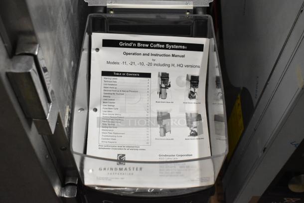 Grindmaster Grind'n Brew-10H stainless steel coffee maker, includes manual. Features hot water dispenser, metal brew basket.