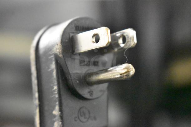 Close-up of a power plug, possibly part of the 2022 True TVM-48SL-HC commercial cooler. Shows plug prongs and minor wear.