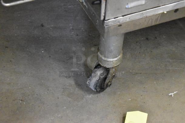 Close-up of a commercial caster wheel on a Middleby Marshall PS638G stainless steel conveyor pizza oven.