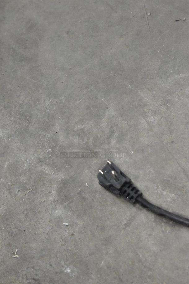 Power cord for KoolMore KM-MDR-1GD-10C reach-in cooler, black three-prong plug on concrete floor.