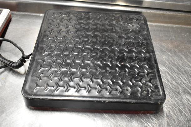 Rubbermaid 150-pound capacity scale, black, textured surface, rectangular shape, minor wear on edges, includes cord.