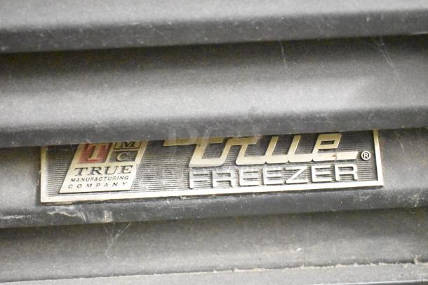 True GDM-35F metal commercial freezer tag, showcasing brand logo and model. Durable 2-door design with poly-coated racks.