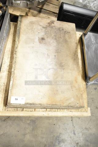 Two pizza oven stones stacked, showing signs of use with minor surface discoloration, marked "59 QTY" on wood pallet.