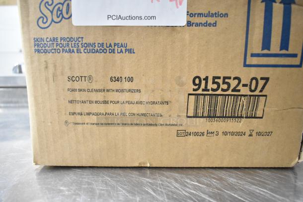 Box labeled Scott Foam Skin Cleanser with moisturizers. Lot 2410026, expires 10/2024. Auction includes Purell dispenser, Aqua Sparkle detergent.