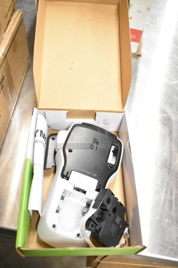 Brand new Dymo LabelManager 160 in open box with manual. Includes cartridge. рядом: Staples Computer Paper box.