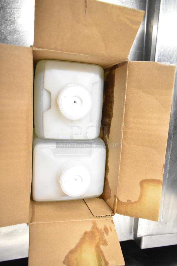 Open box with two white plastic jugs inside, likely containing cleaning products. Box shows signs of liquid stains.