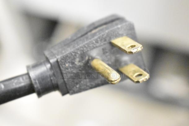 Close-up of a three-prong electrical plug compatible with the True T-49 cooler. Shows standard 115V configuration.