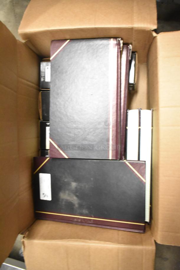 Box containing approximately 25 items, including black notebooks, copy paper reams, and a Lexmark printer cartridge.