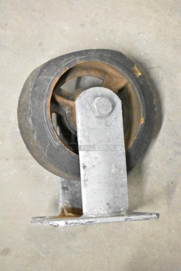 Metal caster wheel with mounting bracket in used condition, showing rust on wheel and bracket. Part of mixed item lot.