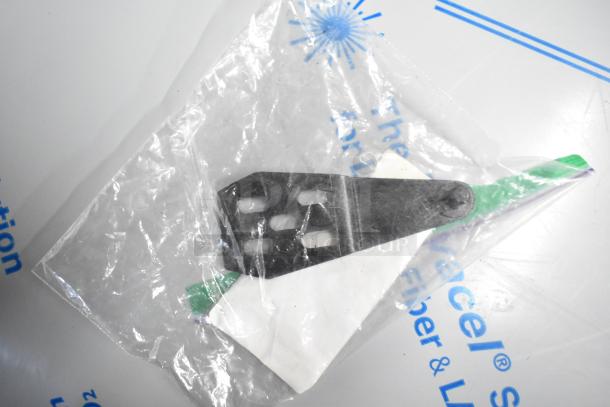 Clear plastic bag containing black metal bracket with rectangular slots, showing partial packaging and printed text.