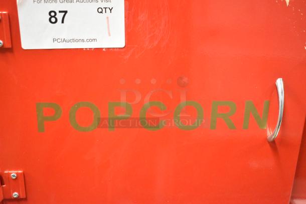 Brand new metal commercial popcorn machine cart, red, minor scratches, "POPCORN" label, ready for merchandising.