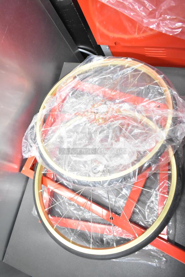 Brand new scratch and dent metal commercial popcorn machine cart, wheels in packaging, red frame visible.