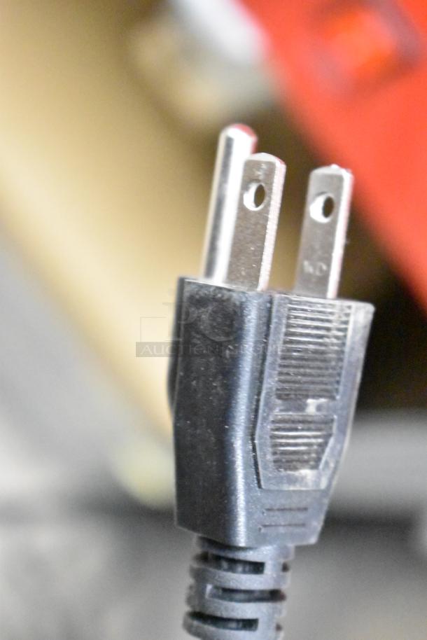 Close-up of a power plug, part of a new scratch and dent metal commercial popcorn machine and merchandising cart.