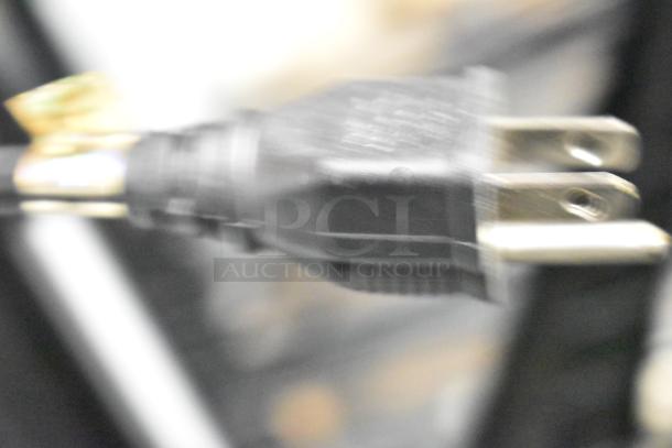 Blurry close-up of a black electrical plug with no visible details on the Marco Display Specialties merchandiser cabinet.